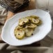 A Villeroy & Boch white porcelain oval pickle dish with pickles on a table.