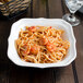 A Villeroy & Boch white porcelain square salad bowl filled with pasta and shrimp.
