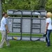 A man and woman carrying a Lifetime plastic picnic table with attached benches.