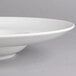 A white porcelain deep plate with a small rim and a well.