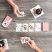 A group of people playing cards with a "Bee" Jumbo Font deck on a wood table.