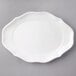 A white porcelain oval plate with a scalloped edge.