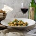 A white Villeroy & Boch porcelain coupe deep plate with food and wine on a table.