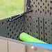 A green rolled up Lifetime outdoor storage box mat inside a grey bin.