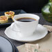 A Villeroy & Boch white porcelain saucer with a cup of coffee on it.