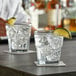 A bartender pouring a drink into Anchor Hocking New Orleans Rocks glasses on a bar table.