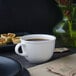 A white Villeroy & Boch porcelain cup of coffee sits on a table next to pastries.