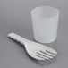 A white plastic measuring cup with a plastic spoon.
