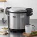 An Avantco stainless steel rice warmer with a bowl of rice and peas.