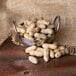 A metal bowl of Hampton Farms roasted unsalted in-shell peanuts on a table.