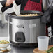 A woman using an Avantco commercial rice cooker to make rice in a professional kitchen.