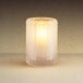 A lit Sterno Paragon frosted fluted candle holder on a table.