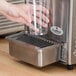 A hand holding a plastic cup over a Crathco refrigerated beverage dispenser.