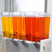 A Crathco refrigerated beverage dispenser with three bowls filled with orange liquid.