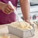 A white-handled boar bristle pastry and basting brush being used to apply a coating to dough in a loaf pan.