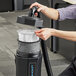 A man using a Lavex backpack vacuum to clean a room in a professional kitchen.