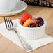 A close-up of a Tuxton fluted white ramekin with fruit in it.