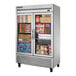 A True 2 section glass door reach-in freezer filled with a variety of food items.