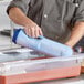 A person using a Vollrath Insta Chill Cooling Paddle to pour liquid into a plastic container.