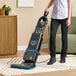A person using a Lavex 15-inch dual motor upright bagged vacuum cleaner with HEPA filtration on a carpet.