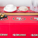 A table with a San Francisco 49ers tablecloth, plates, and cups.