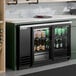 A black glass door back bar refrigerator with LED lighting, stocked with bottles and cans.