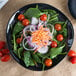 A Reserve by Libbey Pebblebrook obsidian porcelain bowl filled with spinach salad, tomatoes, and onions.