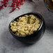 A Reserve by Libbey Pebblebrook obsidian porcelain dip dish filled with green sauce on a table.