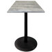 A Holland Bar Stool outdoor table with a gray stone top and black round base.