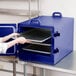 A woman opening a Cambro navy blue insulated tray carrier.