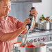 A man using a KitchenAid immersion blender to make soup.