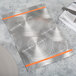 A Menu Solutions Alumitique menu board with orange bands on a table with a knife and fork.