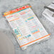 An Alumitique menu board with orange bands on a table with a plate, knife, and fork.