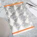 A silver Menu Solutions Alumitique menu board with orange bands on a table with silverware and a white napkin.