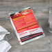 A Menu Solutions Alumitique menu board with red bands on a table with a fork and knife.