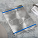 A Menu Solutions Alumitique aluminum menu board with royal blue bands on a table.
