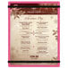 A pink Menu Solutions acrylic menu board with rubber band straps on a table in a restaurant.