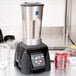 A Waring commercial blender on a counter with a container of strawberries.