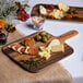 An American Metalcraft faux acacia melamine serving peel with cheese, olives, and dried orange slices on a table.