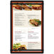 A black customizable acrylic menu board with rubber band straps displaying a sandwich and salad.