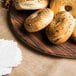 An American Metalcraft faux acacia melamine serving board with bagels and napkins on a table.