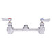 A Fisher stainless steel wall-mounted faucet base with lever handles and swivel outlets.