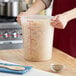 A person holding a Choice translucent plastic container full of pasta.