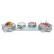 A Rosseto rectangular clear tempered glass riser shelf on a buffet table with food on it.