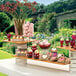 A rectangular natural bamboo riser shelf holding a variety of desserts on a table.