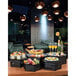 A black matte hexagon riser on a table with food and drinks.