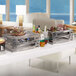 A stainless steel Rosseto chafer alternative with food on a metal tray.