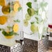 A Rosseto clear plastic rectangle beverage dispenser filled with water, orange slices, and green leaves.
