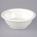 A Tuxton eggshell white china footed salad bowl on a gray surface.