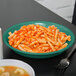 A rainforest green melamine bowl filled with pasta and sauce with a fork on the side.